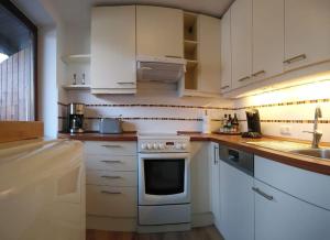 una cucina con armadi bianchi e piano cottura di Wohnung direkt am Tegernsee mit XL-Terrasse a Gmund am Tegernsee