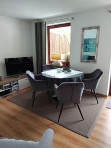 Wohnung direkt am Tegernsee mit XL-Terrasse في غموند آم تيغرنسي: غرفة معيشة مع طاولة طعام وكراسي
