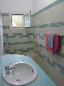 uma casa de banho com um lavatório, uma janela e toalhas em KEUR DIAM - Maison de la Paix em Saly Portudal