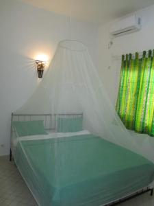 a bedroom with a bed with a mosquito net at KEUR DIAM - Maison de la Paix in Saly Portudal