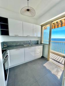 cocina con armarios blancos y vistas al océano en « LA SUITE »Superbe appartement NEUF, Front de mer, en Menton