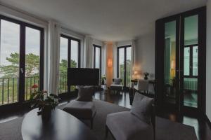 uma sala de estar com um sofá, cadeiras e janelas em A-ROSA Collection Hotel Ceres am Meer em Binz