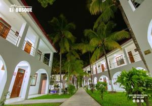 a row of white buildings with palm trees in front at Hotel El Bosque in Jaén