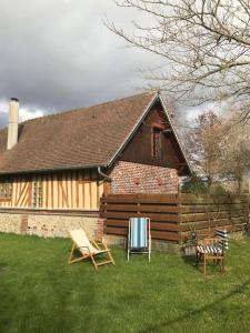 dom z dwoma krzesłami w trawie przed nim w obiekcie La Laiterie Normande w mieście Saint-Denis-de-Mailloc