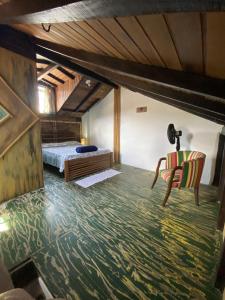 a bedroom with a bed and a chair at Suítes no Centro Histórico de Paraty in Paraty