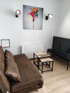 a living room with a couch and a television at L'Atelier de l'Artiste - Moulins Cœur de ville in Moulins