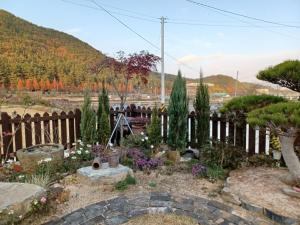 einen Garten mit Blumen und Bäumen vor einem Zaun in der Unterkunft Iryang Stay in Goseong