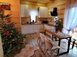 a kitchen with a christmas tree and a table and chairs at Zymbiańsko Chałupa 1 z balią na wyłączność in Ząb