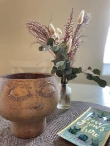 a vase with a face on it next to a book at Appart Cosy 2 chambres in Bruz