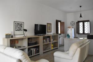 a living room with two white chairs and a tv at Le Radici Home in LʼAquila