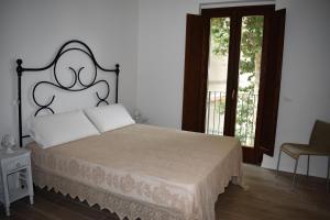 a bedroom with a bed with a headboard and two windows at Le Radici Home in LʼAquila