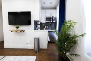 a kitchen with white cabinets and a tv on the wall at 69-2D Stylish Lower East Side 1BR Apt BRAND NEW in New York