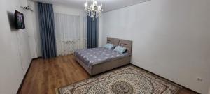 1 dormitorio con cama, alfombra y lámpara de araña en Квартира, en Atyraū