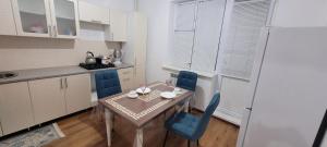 a small kitchen with a table and blue chairs at Квартира in Atyraū