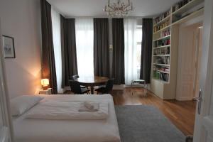 a bedroom with a bed and a table and a chandelier at Casa Nostra - Ausgefallene Wohnung am Augarten in Vienna
