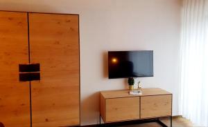 a living room with a tv and a wooden dresser at Traum-Maisonette auf 1.000m mit Pool und Sauna in Schönwald
