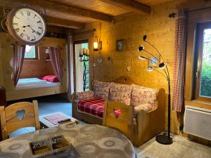 een woonkamer met een klok aan de muur en een slaapkamer bij Chalet d' Annelise in Gérardmer