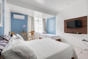 a hotel room with a bed and a tv at Flamboyant Hotel in Barra Velha