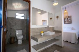 a bathroom with a sink and a toilet and a bed at Arandu Casa Hotel Quadrado in Trancoso