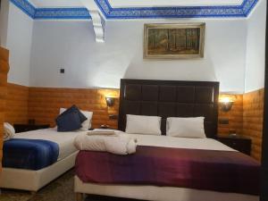 ein Schlafzimmer mit 2 Betten und einem Wandgemälde in der Unterkunft Riad Kanata in Marrakesch
