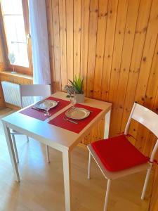 una mesa blanca con 2 sillas y un mantel rojo en Studio cosy au centre du village, en Evolène