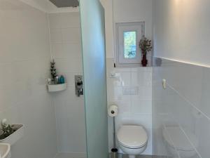 ein weißes Bad mit einem WC und einem Fenster in der Unterkunft CASALINO DI ANNA in Wensickendorf