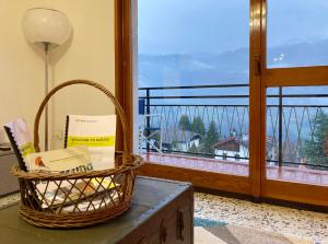una cesta de libros sentada en una mesa junto a una ventana en Bellavista - Residence in Barzio center near free ski shuttle, en Barzio