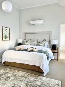 a bedroom with a large bed with white sheets and pillows at The Village Cottage in Franschhoek