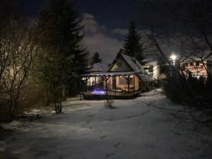 une maison dans la neige la nuit dans l'établissement Vadgalamb Apartman & Jacuzzi, à Miskolctapolca