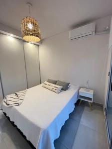 a bedroom with a white bed and a lamp at DEPARTAMENTO CENTRICO in Bahía Blanca