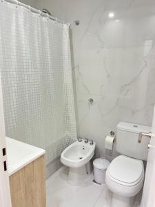 a white bathroom with a toilet and a shower at DEPARTAMENTO CENTRICO in Bahía Blanca