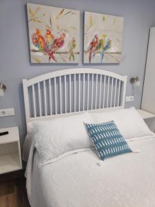 um quarto com uma cama branca e duas pinturas na parede em LA CASA DE VIOLETA em Suances