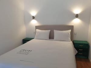 1 dormitorio con 1 cama blanca grande y 2 mesitas de noche en Casa do Moleiro en Mortágua