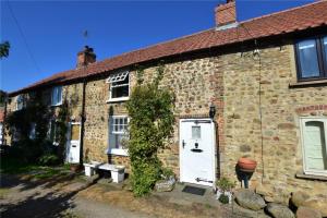 an old stone house with a white door and ivy at Granny Vera's @ Marigold Cottage in Bedale