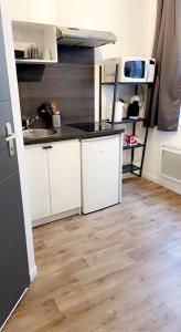 a kitchen with white cabinets and a wooden floor at Studio confortable au cœur de Rouen in Rouen