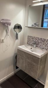 a bathroom with a sink and a hair dryer on the wall at Studio confortable au cœur de Rouen in Rouen