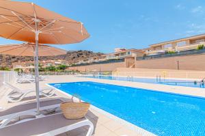 basen z krzesłami, parasolem i basenem w obiekcie Black Beach Luxury Vacation House w mieście Puerto de Santiago