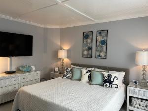 a bedroom with a bed with pillows and a flat screen tv at Sandpiper SC Luxe Oceanview Condo in Private Paradise in Oceanmarsh Subdivision