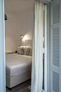 a white bedroom with a bed and a white curtain at Romantic apartment with hot tub next to Acropolis in Athens