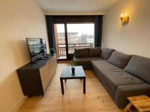 a living room with a couch and a television at Résidence le WAALA , face aux pistes in Les Deux Alpes