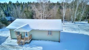 ein kleines Haus mit Schnee auf dem Dach in der Unterkunft Hjort cottage - 4 Bedrooms 9 people 2 bathrooms in La Macaza