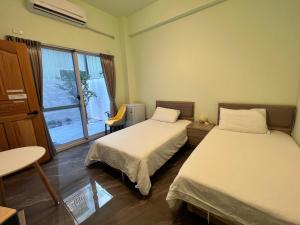 a room with two beds and a table and a window at Xingda Port Homestay 