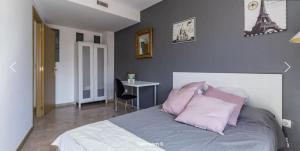 1 dormitorio con cama con almohadas rosas y escritorio en Atico Duplex Luminoso, en Valencia