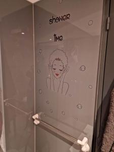 um chuveiro de vidro com um desenho de uma mulher em cocon douillet avec ambiance du feu au bois em Hastière-par-delà