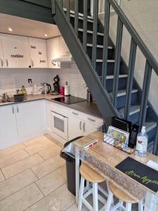 a kitchen with white cabinets and a staircase at cocon douillet avec chaleur ambiante du poêle à pellets in Hastière-par-delà