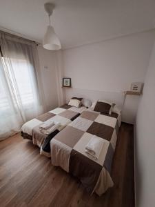 Un dormitorio con dos camas y una gran ventana. en Apartamento la moraña, en Arévalo