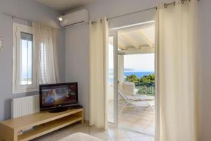 sala de estar con TV y balcón en Βίλα με Υπέροχη Θέα Porto Cheli Villa Luxury Kounoupisea, en Agios Aimillianos