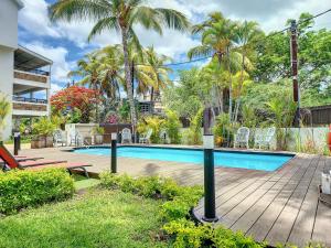 - une piscine bordée de chaises et de palmiers dans l'établissement Sunkissed - Brand New Beach apartment located 50m from beach, à Flic-en-Flac