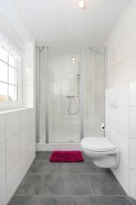 a white bathroom with a shower and a toilet at Pension Burggaststätte Heyken in Neuharlingersiel