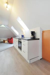 eine Küche im Dachgeschoss mit weißen Schränken und einem Herd in der Unterkunft Pension Burggaststätte Heyken in Neuharlingersiel